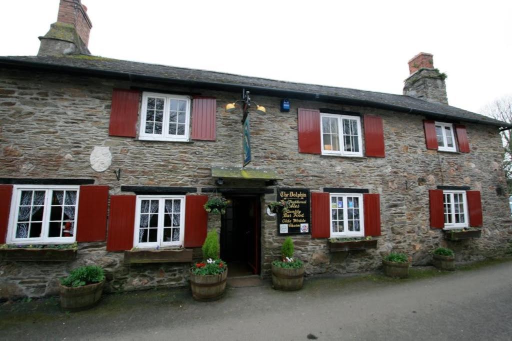 an old stone building with red shuttered windows and a door at The Dolphin Inn in Kingsbridge