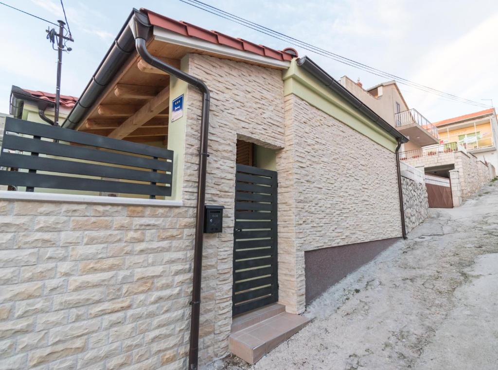 a brick building with a black garage door at Modern Apartment Baćo with Jacuzzi in Šibenik