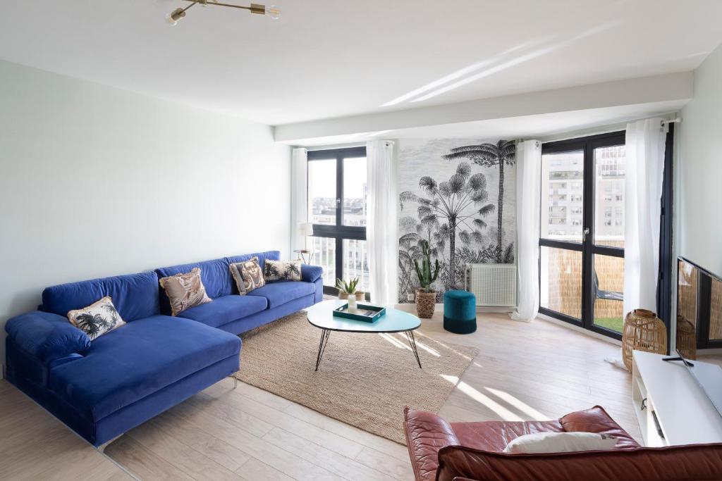 un salon avec un canapé bleu et une table dans l'établissement Angèle by Cocoonr, à Rennes