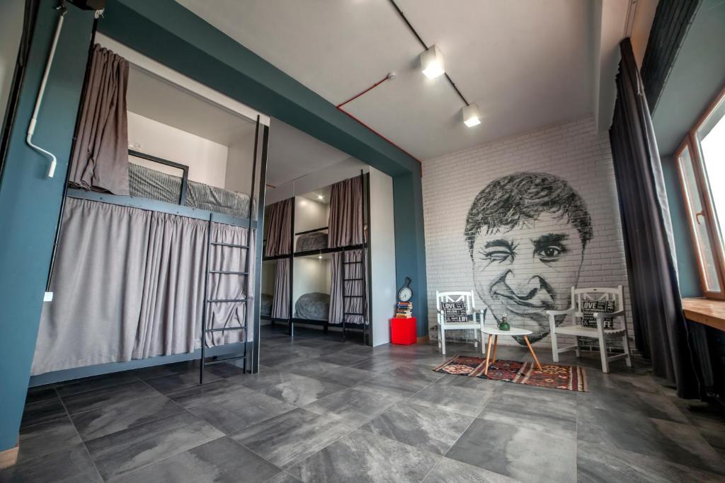 une chambre avec une fresque murale représentant une tête sur le mur dans l'établissement LOFT Hostel, à Gyumri