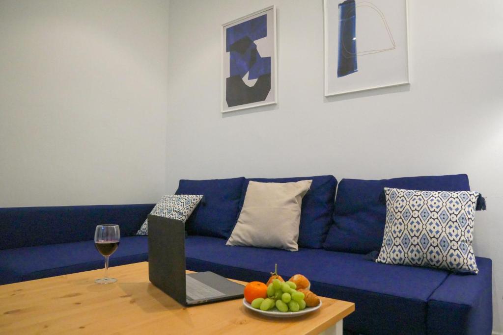ein blaues Sofa im Wohnzimmer mit einer Schale Obst in der Unterkunft Stay U-nique Apartments Sant Eudald in Barcelona