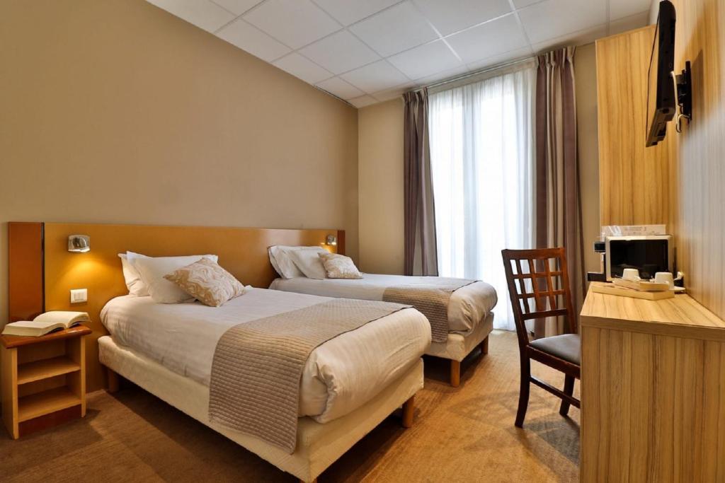 a hotel room with two beds and a desk at Hotel le Noailles Nice Gare in Nice