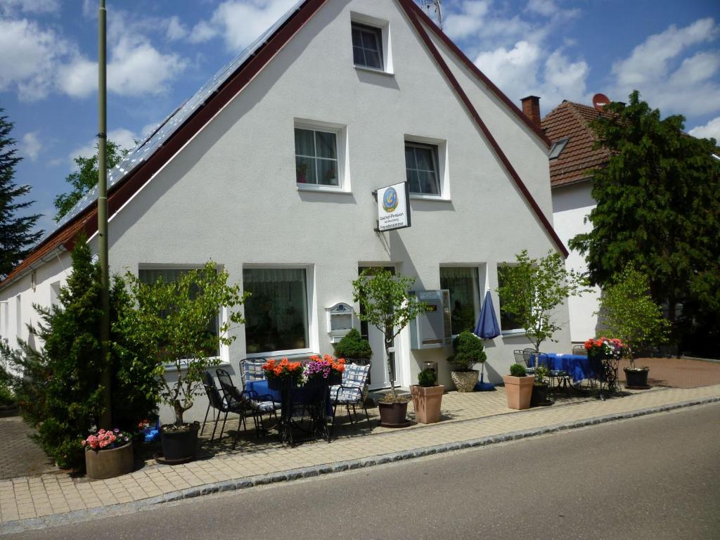 a white house with a table and chairs and plants at Gasthaus - Pension Am Buchberg in Mönchsdeggingen