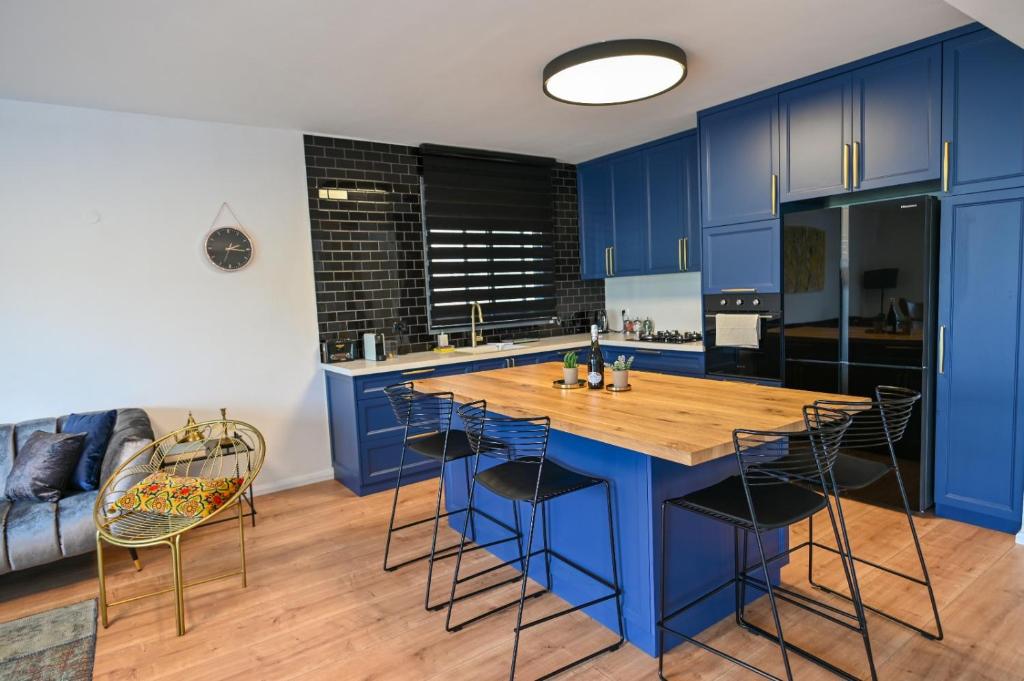 Una cocina con gabinetes azules y una mesa de madera. en Royal Serenity Penthouse, en Tiberíades