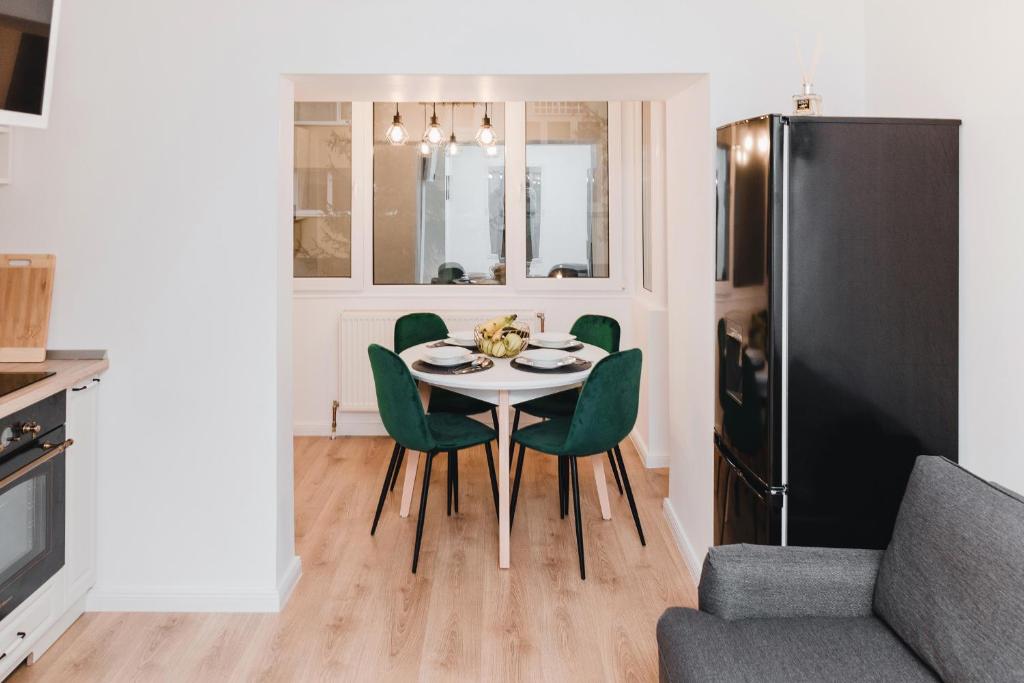 eine Küche mit einem Tisch mit grünen Stühlen und einem Kühlschrank in der Unterkunft N&B Apartments in Cluj-Napoca