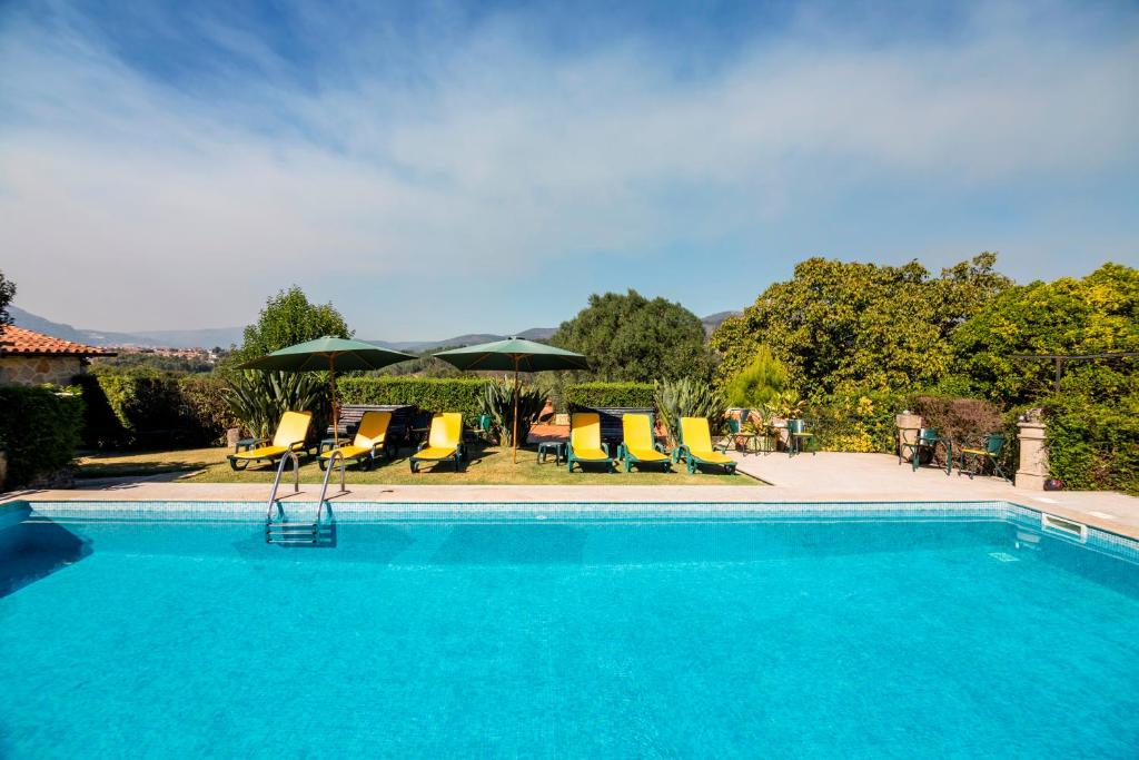 uma piscina com cadeiras e guarda-sóis em Quinta Da Aldeia em Ponte de Lima