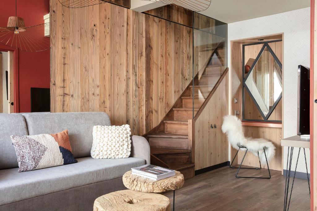 a living room with a couch and a staircase at Grandes Rousses Hotel & Spa in L'Alpe-d'Huez