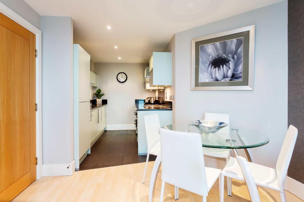 a kitchen and dining room with a glass table and white chairs at Veeve - River Views from Vauxhall in London