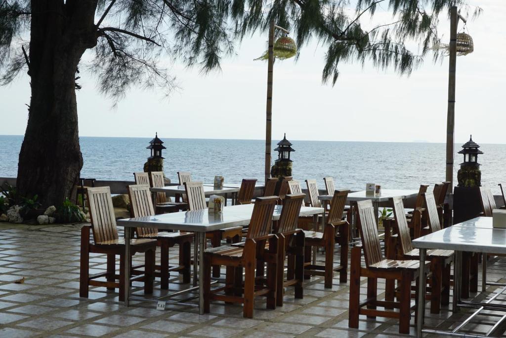 a row of tables and chairs with the ocean in the background at Andaman Beach Resort Koh Jum in Ko Jum