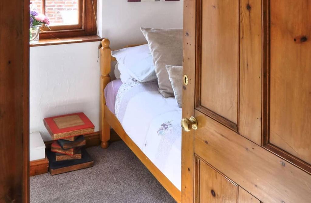 een slaapkamer met een bed met witte lakens en een raam bij Cottages-Whitby in Whitby