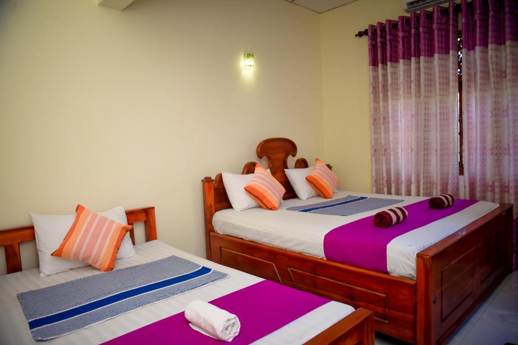 2 aparte bedden in een kamer met paars en wit bij Tissa Rainbow Guest & Yala in Tissamaharama