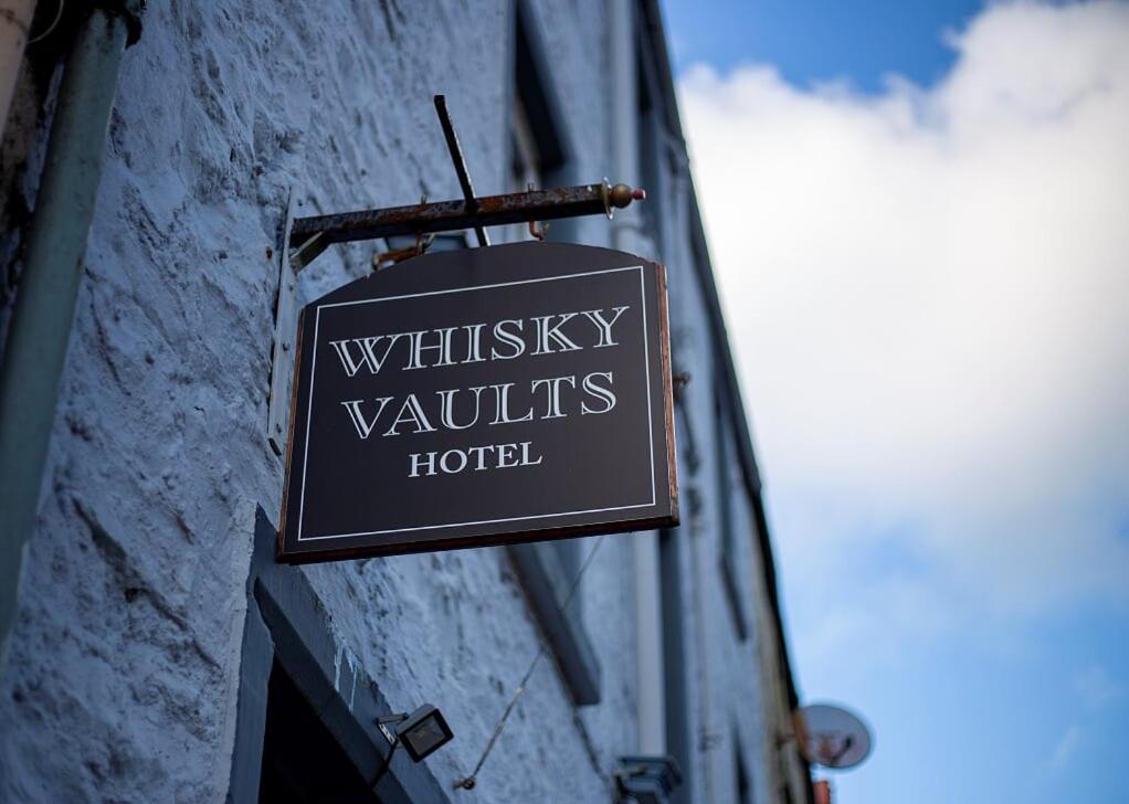 a sign for a hotel hanging on the side of a building at The Whisky Vaults in Oban
