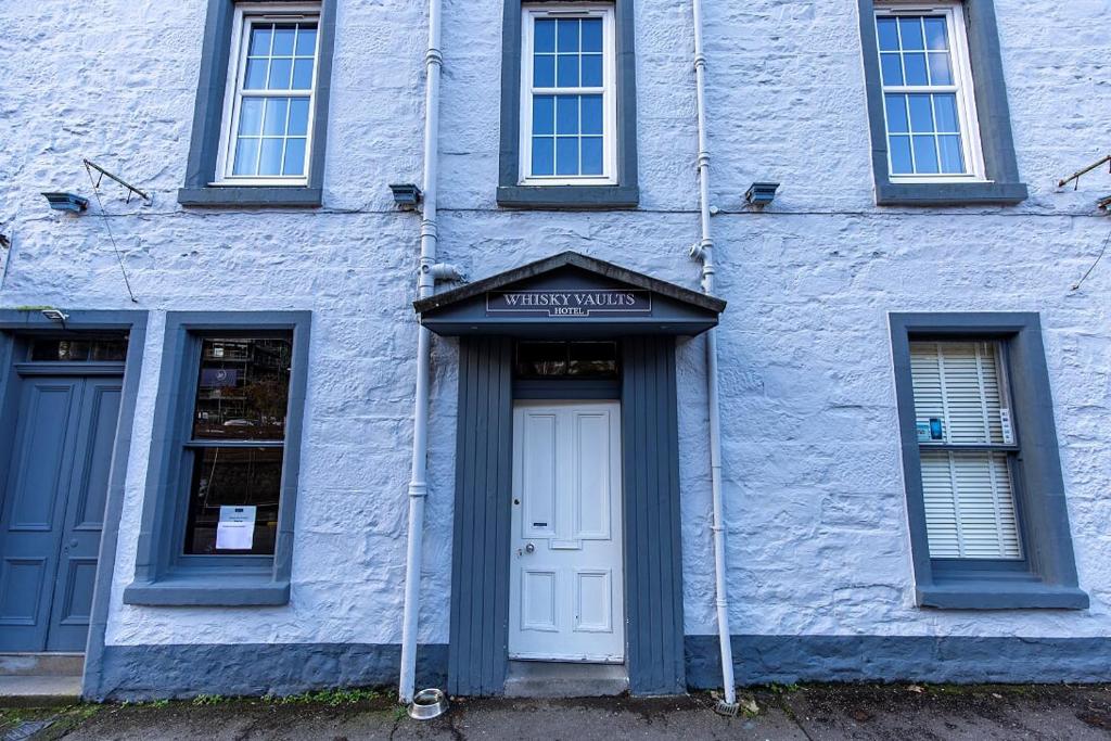 um edifício azul com uma porta branca e janelas em The Whisky Vaults em Oban