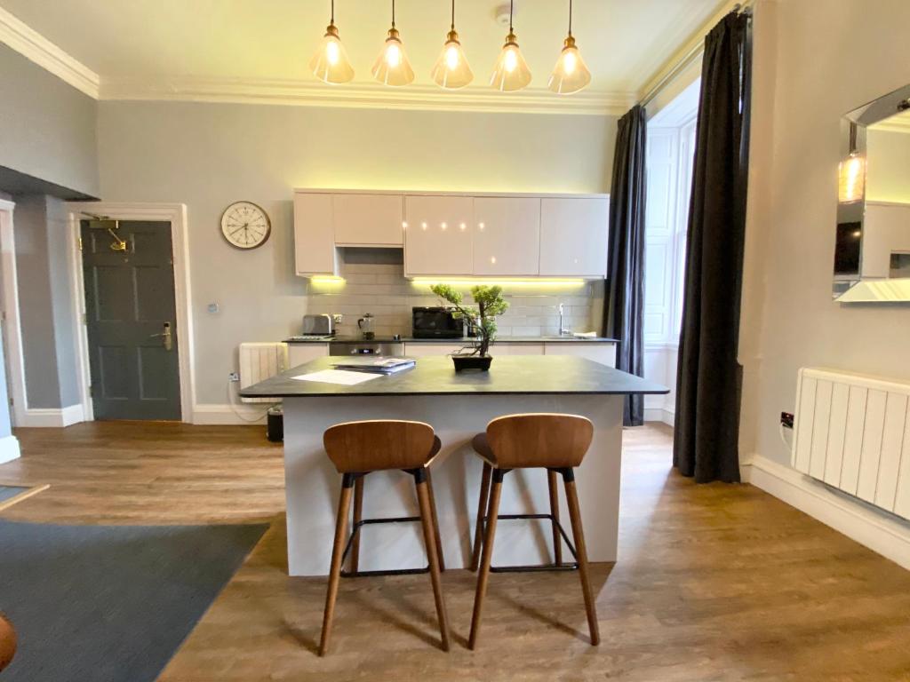 a kitchen with a island with two bar stools at The Waterhouse at Claremont Apartments in Leeds