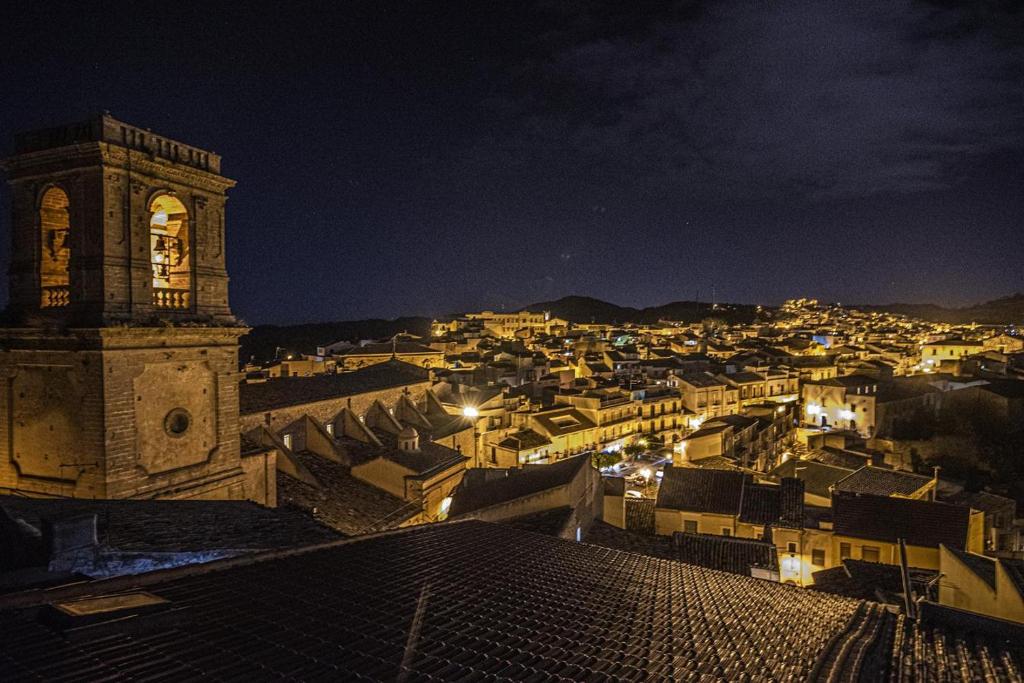 Blick auf eine Stadt in der Nacht mit einem Uhrturm in der Unterkunft Experience Il Paesino in Licodia Eubea