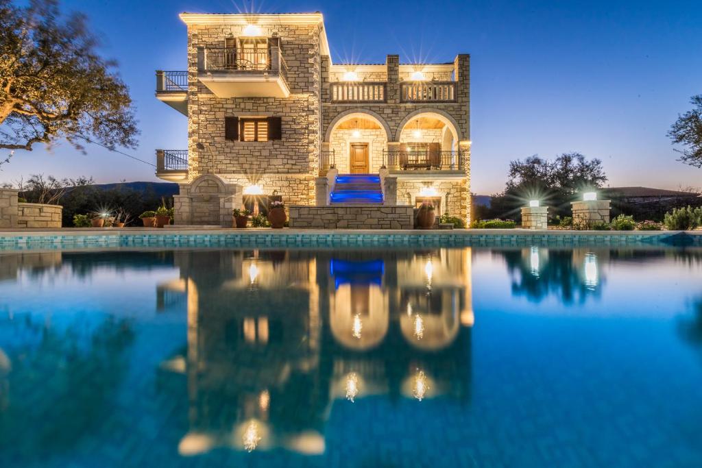 a villa with a swimming pool at night at Filoxenia Stone House in Kalpaki