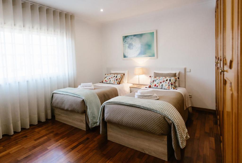 two twin beds in a room with a window at Casa da Calçada II in Guimarães