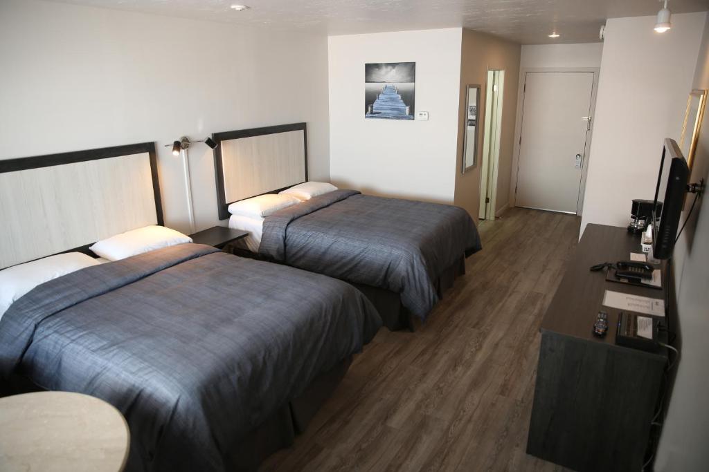 a hotel room with two beds and a television at Motel Castille in Roberval