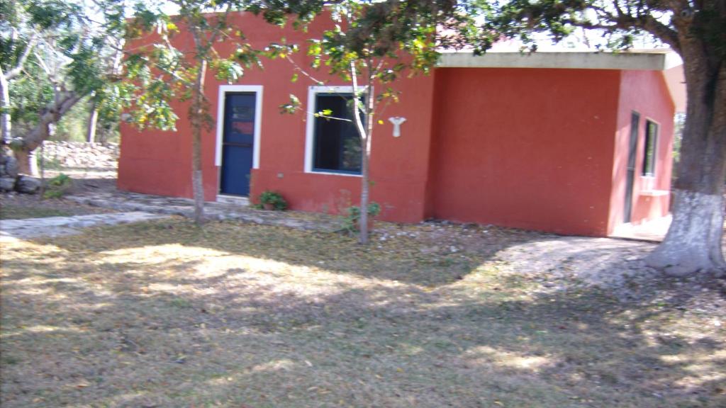 Hacienda San Jose Poniente Blue House في Hoctún: بيت احمر امامه شجره