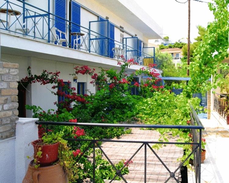 einen Balkon eines Gebäudes mit Blumen und blauen Balkonen in der Unterkunft Myrmidon Hotel in Agia Marina