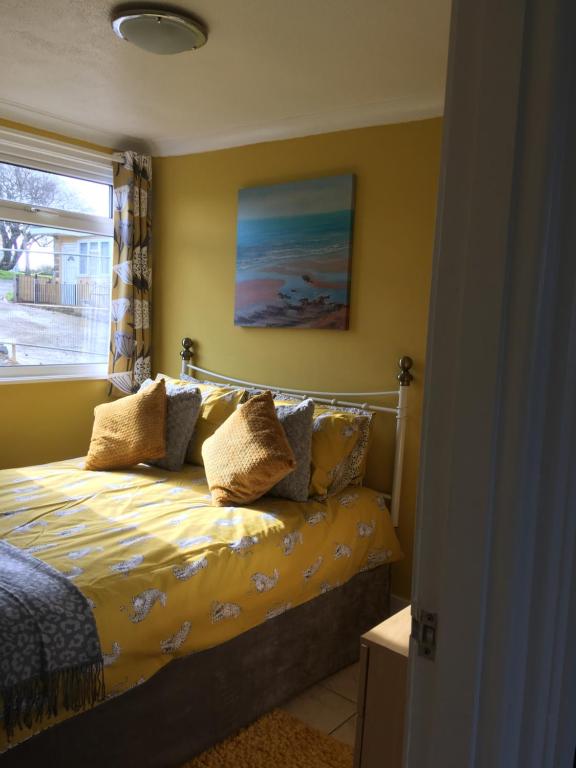 a bedroom with a bed with yellow sheets and a window at 8 Sandy Bottom Sandown Bay Holiday Park, reduced ferry, please contact us in Sandown
