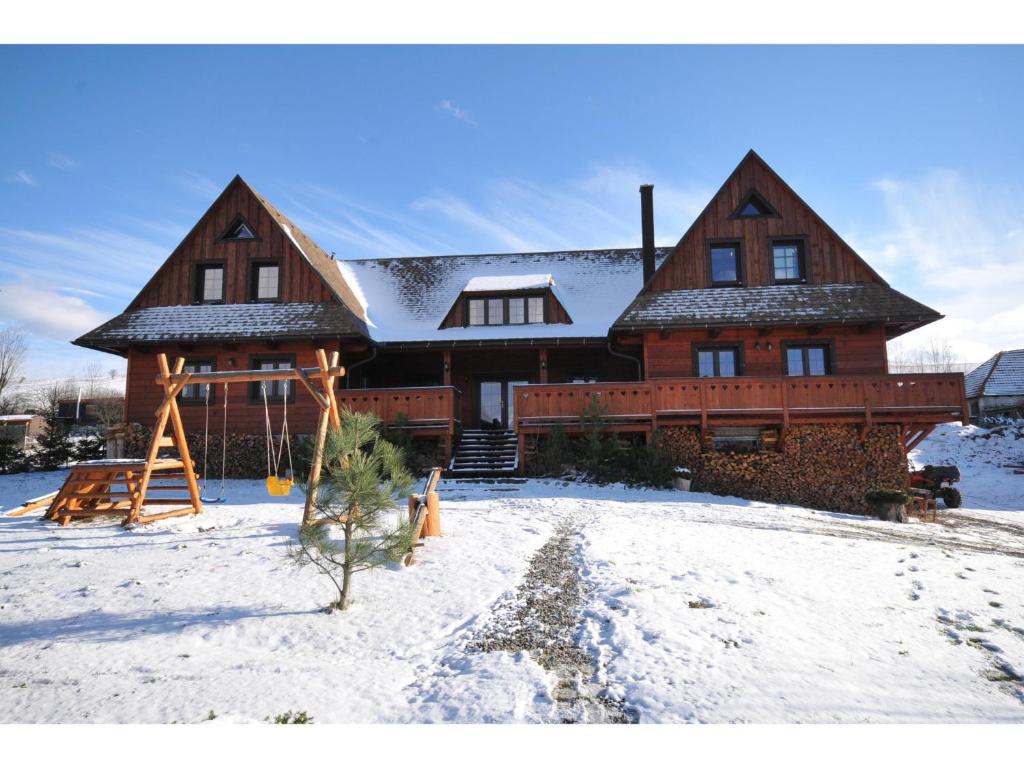 une grande maison en bois avec de la neige au sol dans l'établissement Apartmánová Chalupa, à Liptovský Trnovec