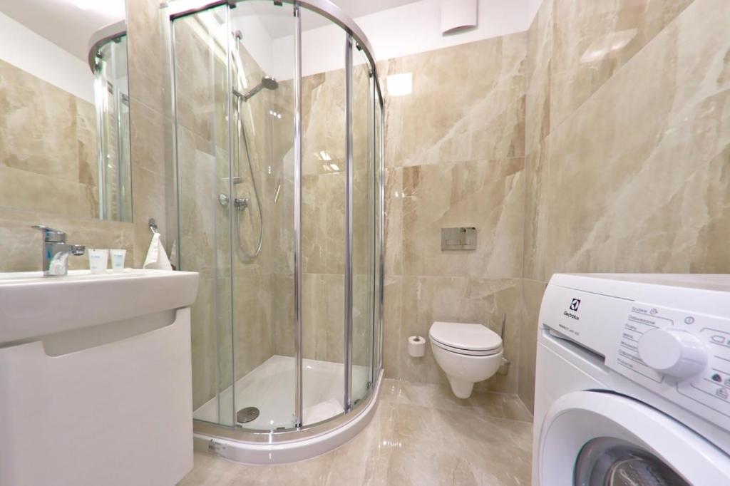 a bathroom with a shower and a washing machine at Apartament MajGraj sąsiedztwo Parku Zdrojowego in Świnoujście
