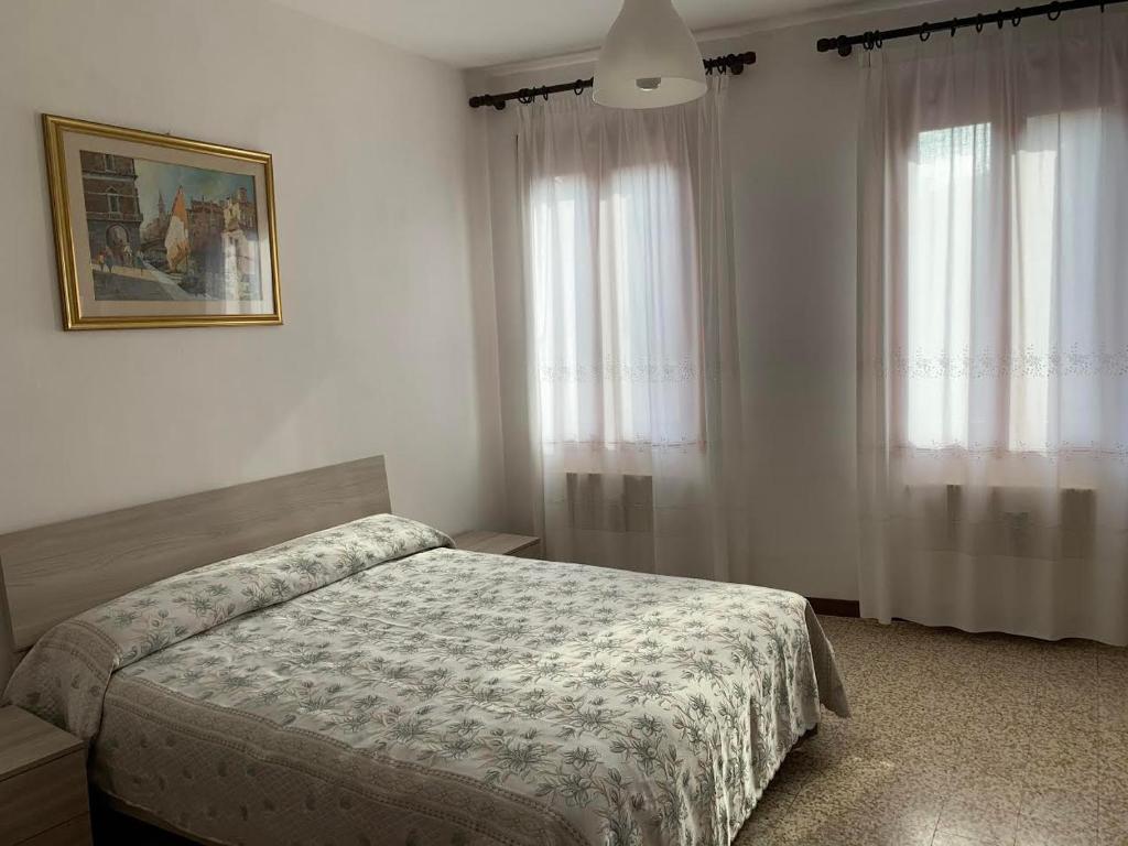 a bedroom with a bed and two windows at Appartamento Damiana in Venice