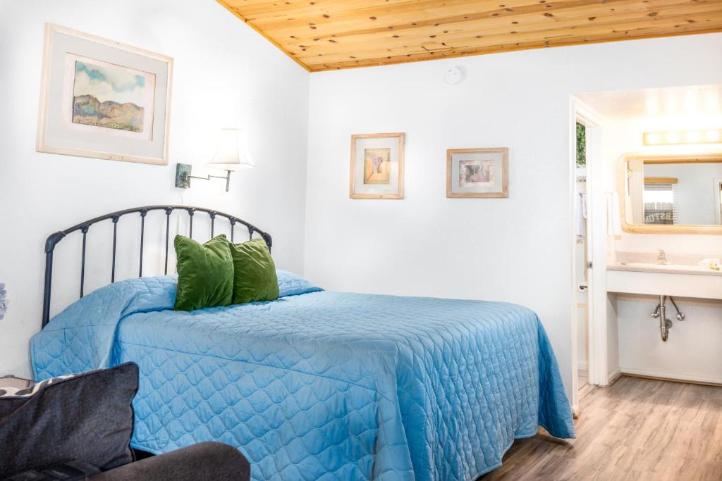 Un dormitorio con una cama azul con almohadas verdes en Larian Motel, en Tombstone