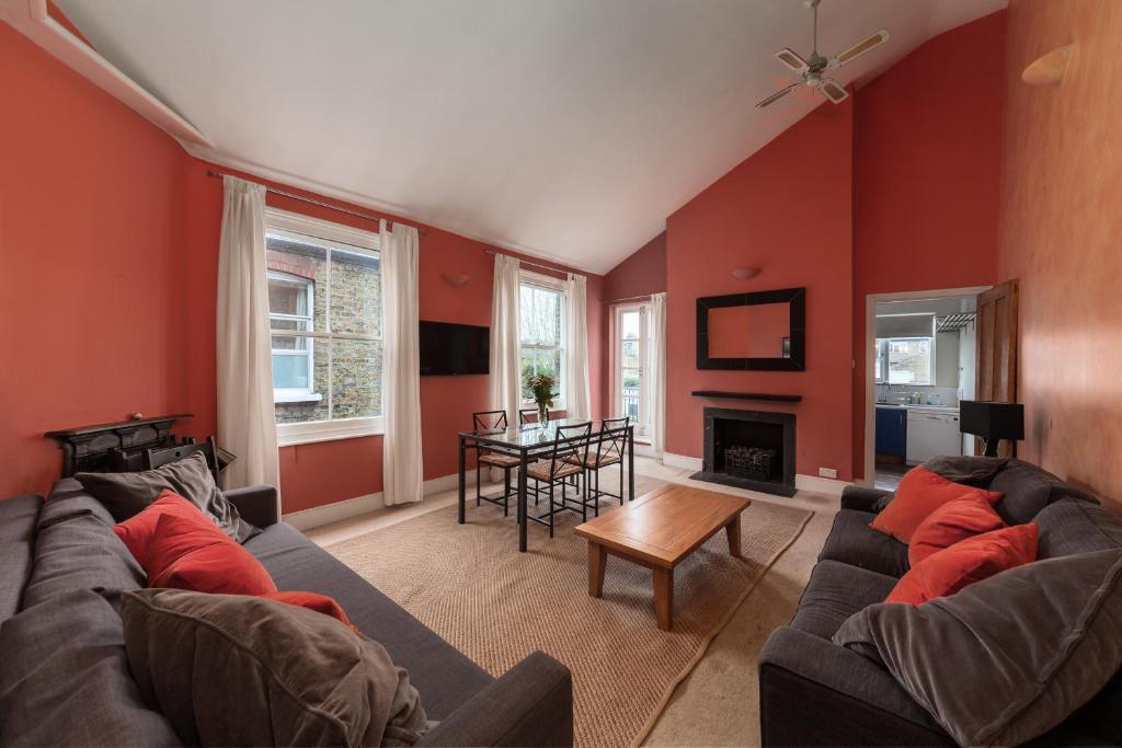 a living room with red walls and a couch and a table at Wix's Lane in London