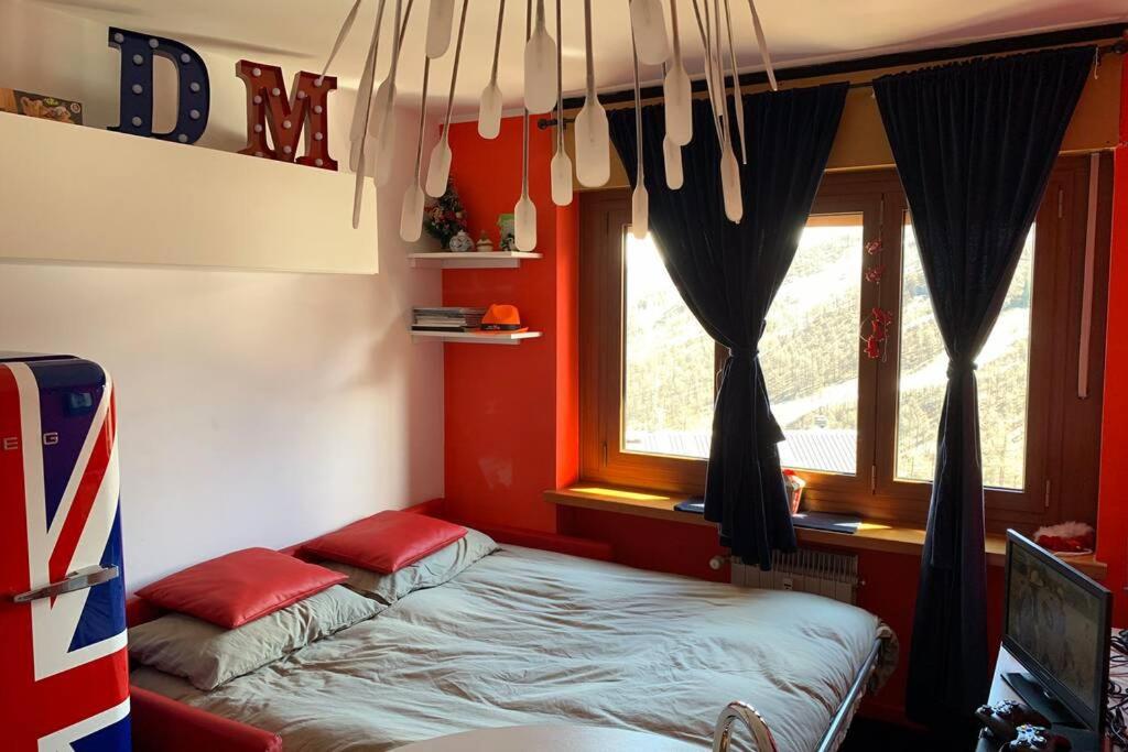 a bed in a room with red walls and a window at A 2 minuti dalle piste da sci e campo da golf. in Sestriere