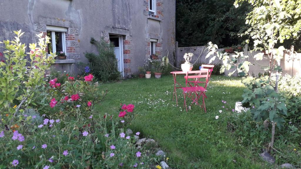 un jardín con 2 sillas, una mesa y flores en Chambre d hôte chez Fany en Mur-de-Bretagne