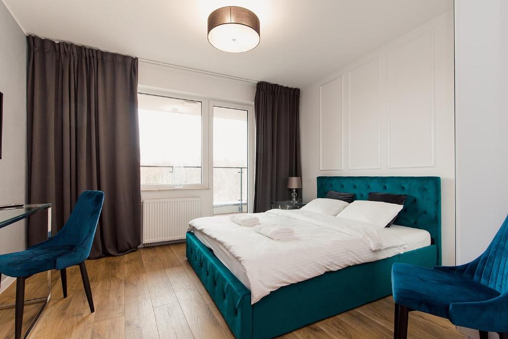 een slaapkamer met een blauw bed en 2 blauwe stoelen bij Warsaw To Be - Glamour Apartment in Warschau