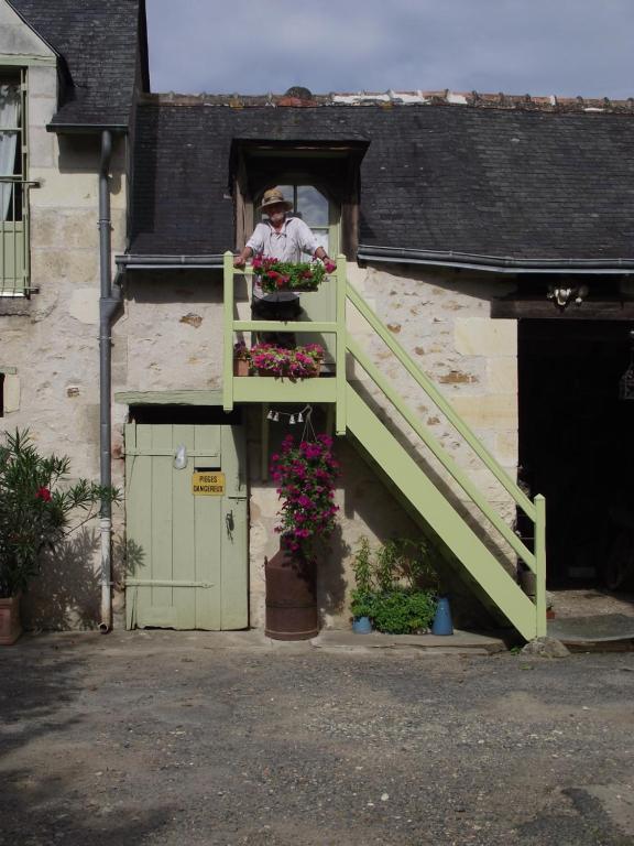un hombre parado en una ventana con una caja de flores en Chambre d'hôtes Le Vaujoint en Cheillé