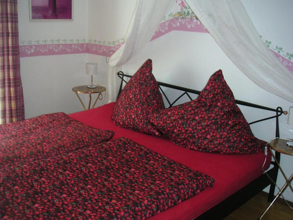 Cama roja con sábanas y almohadas rojas en Natur-Aktiv-Hof Thiem, en Pottenstein