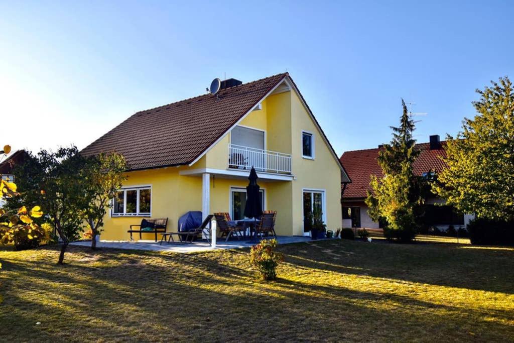 ein gelbes Haus mit einer Terrasse und einem Hof in der Unterkunft Ferienwohnung INGRID in Markt Erlbach