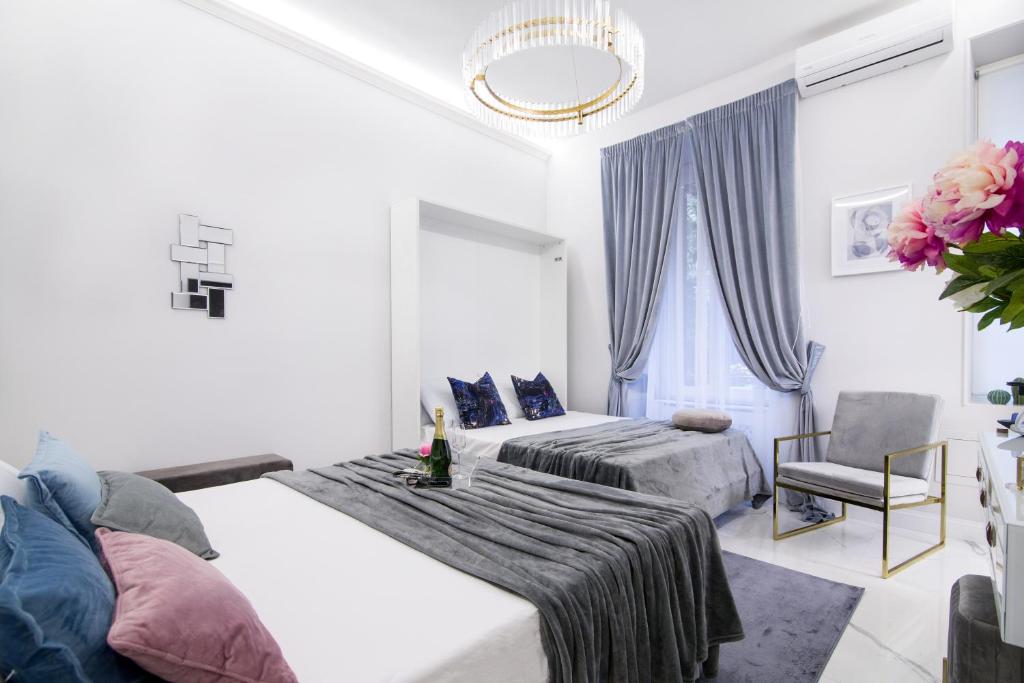 biała sypialnia z 2 łóżkami i krzesłem w obiekcie Roma Deluxe Apartments w Rzymie