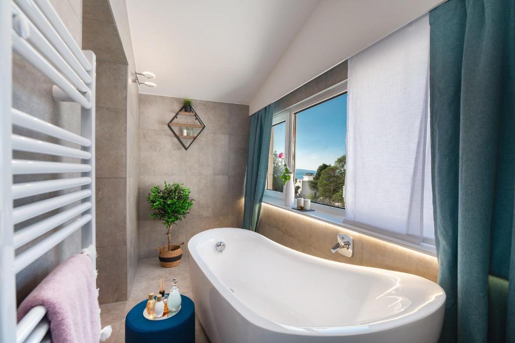 ein Bad mit einer Badewanne und einem Fenster in der Unterkunft Villa Biston in Baška Voda