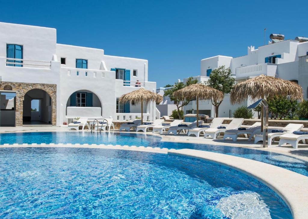 a pool with chairs and umbrellas in front of a hotel at Cycladic Islands Hotel & Spa in Agia Anna Naxos