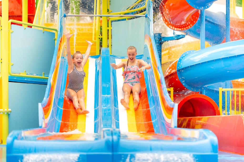 dos niños jugando en un tobogán acuático en un parque acuático en BIG4 Gold Coast Holiday Park, en Gold Coast