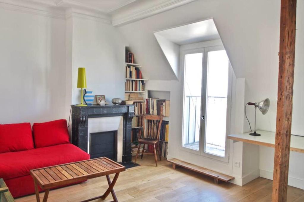 a living room with a red couch and a fireplace at Very Nice Apartment Between Pigalle And Montmartre in Paris