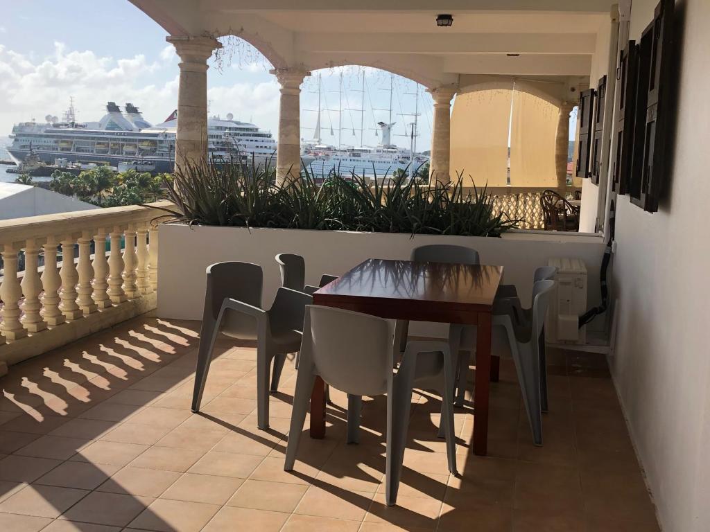 a table and chairs on a balcony with a view of a ship at Maison Saint-Pierre2 in Philipsburg