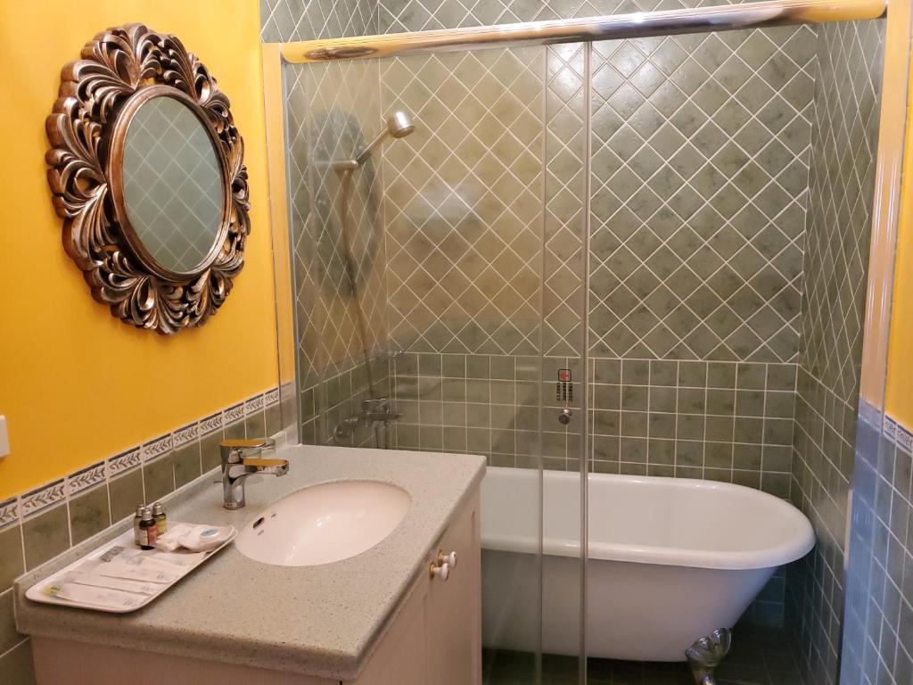 a bathroom with a sink and a tub and a mirror at Haut Rhin Villa in Zhuangwei