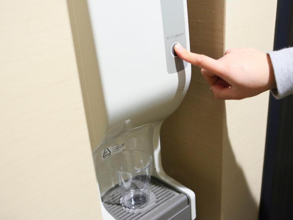 a person pointing at a wine glass in a machine at APA Hotel Tennoji Ekimae in Osaka