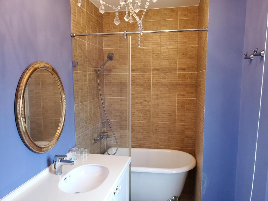 a bathroom with a sink and a mirror and a tub at Haut Rhin Villa in Zhuangwei