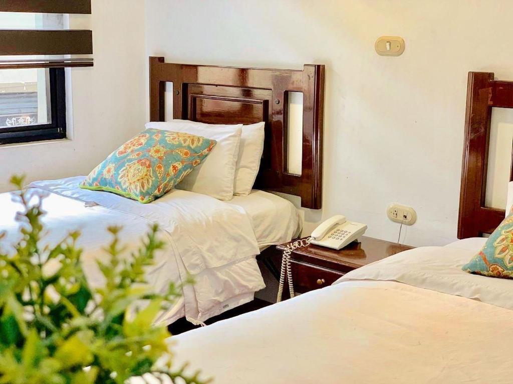 een hotelkamer met 2 bedden en een telefoon bij HOSTAL EL CAJAS in Cuenca