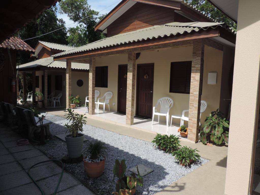 een huis met stoelen en planten op de binnenplaats bij Recanto Abayomi in Ilha do Mel