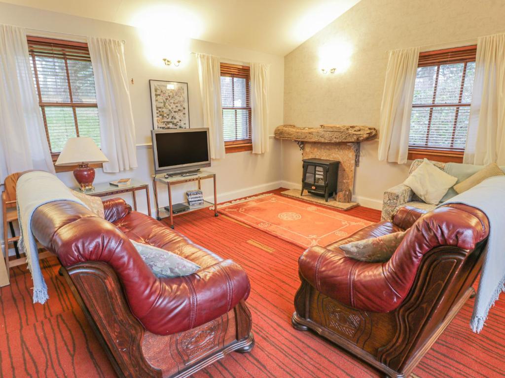 a living room with leather furniture and a fireplace at Mercat Cottage in Port Seton