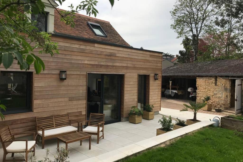 une terrasse avec deux bancs et une maison dans l'établissement Charmante maison rénovée en Pays de la Loire ., à Durtal