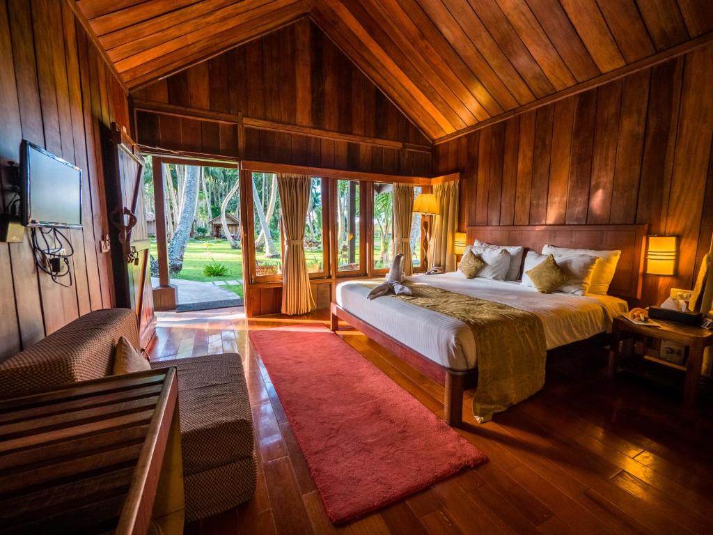 a bedroom with a bed in a room with wooden walls at Sea Shell Resort & Spa, Havelock in Havelock Island